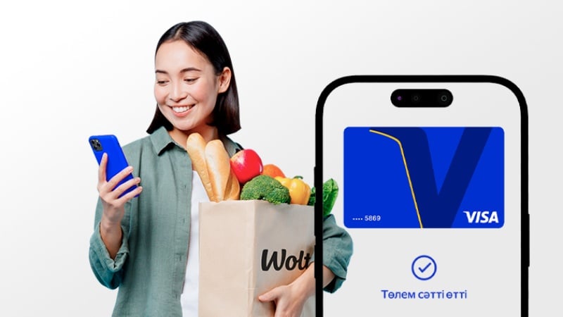 Smiling woman holding Wolt grocery bag and smartphone with successful Visa payment confirmation on screen.