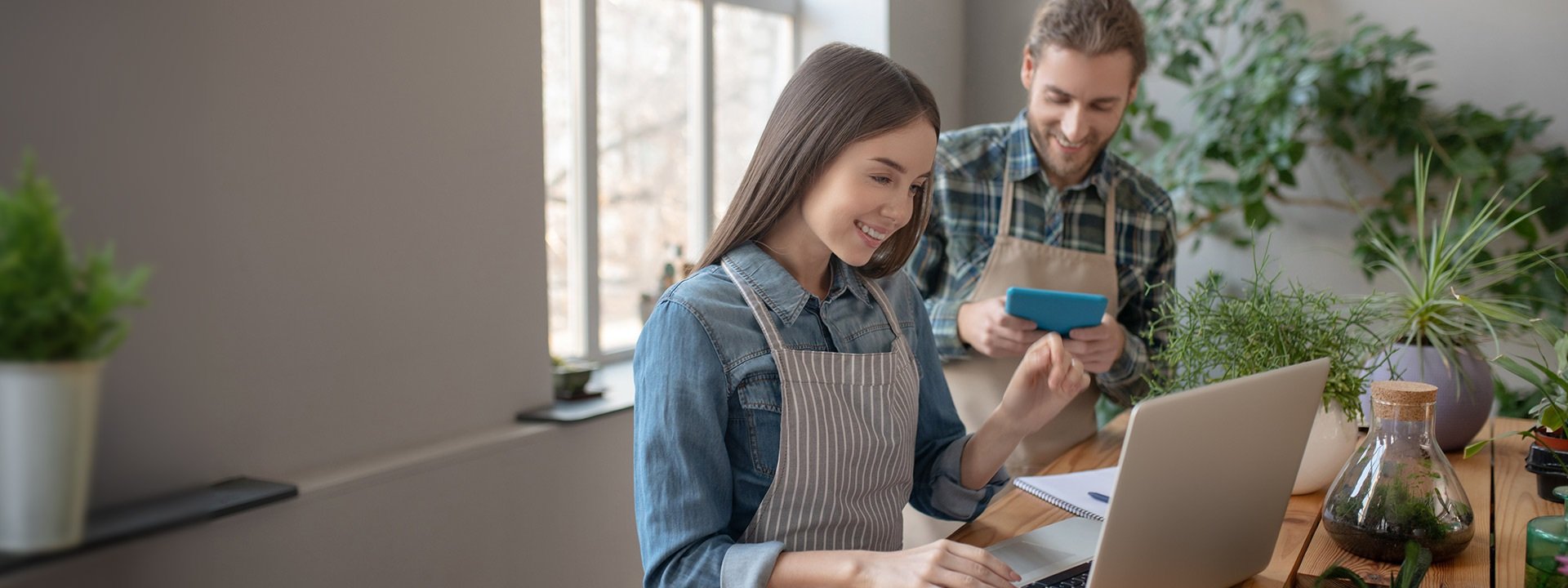 A man with a tablet and a woman with a laptop in a shop