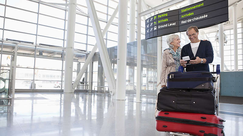 Әуежайдағы жолжүгі бар егде адамдар жұбы Smiling couple with full luggage trolley in airport.