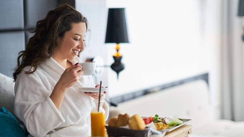 A woman having a breakfast and holding a cup of tea or coffee