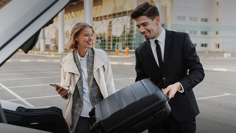A man helps a woman to put her luggage into the car
