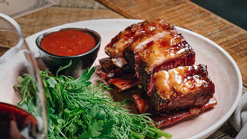 A restaurant dish with meat, greenery and sauce