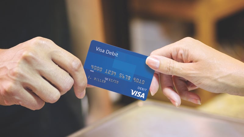 Customer handing over debit card for in-store purchase.